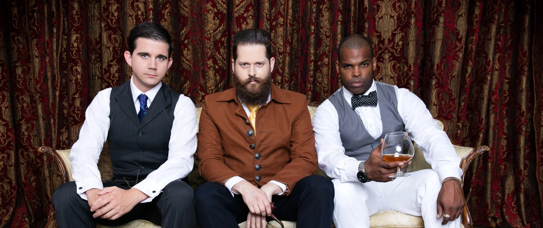Awesome Gentlemen’s Society seated together on a vintage couch