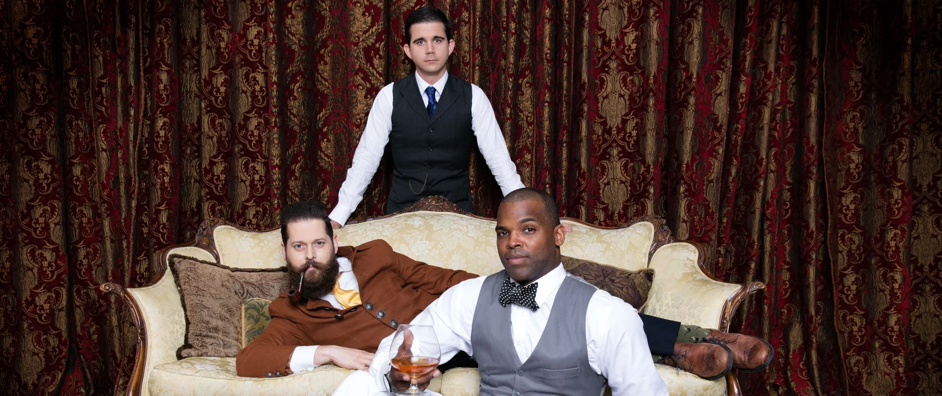 Awesome Gentlemen’s Society posed around a vintage couch