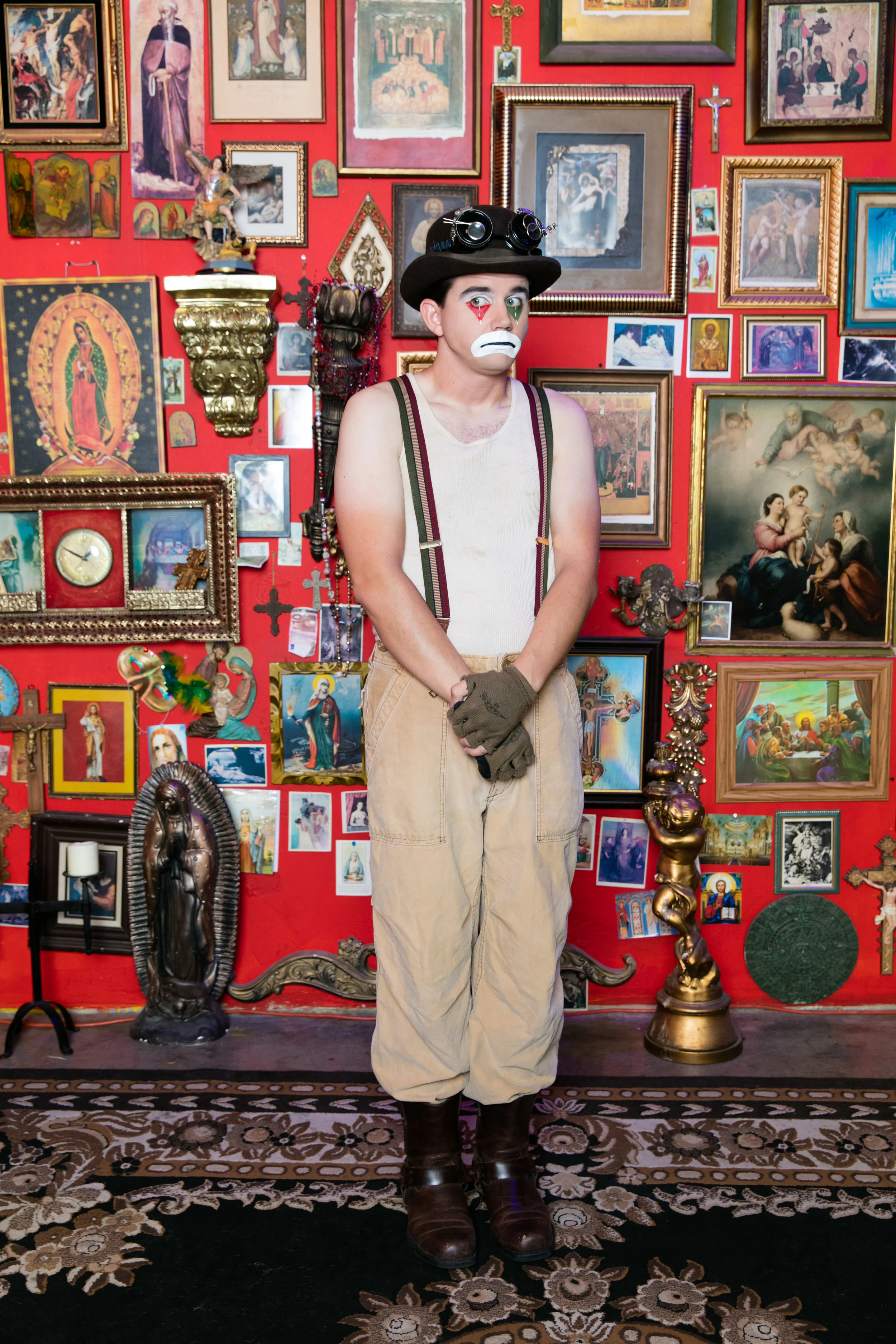 Full-length portrait of Sad Clown Lee against a red gallery wall