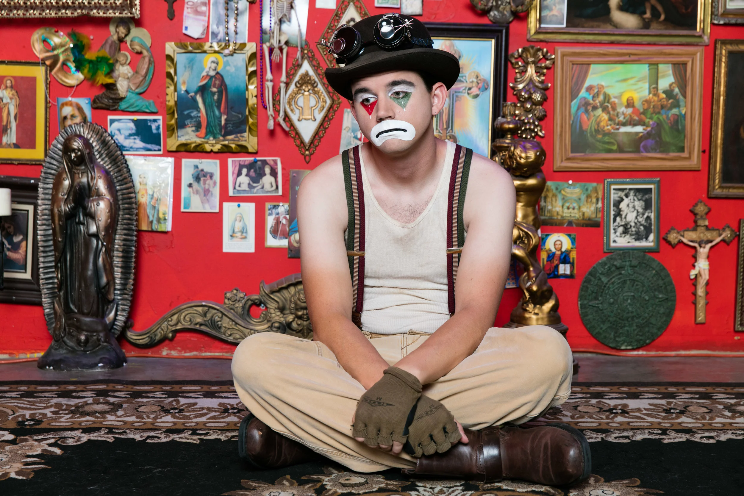 Sad Clown Lee seated against a red gallery wall