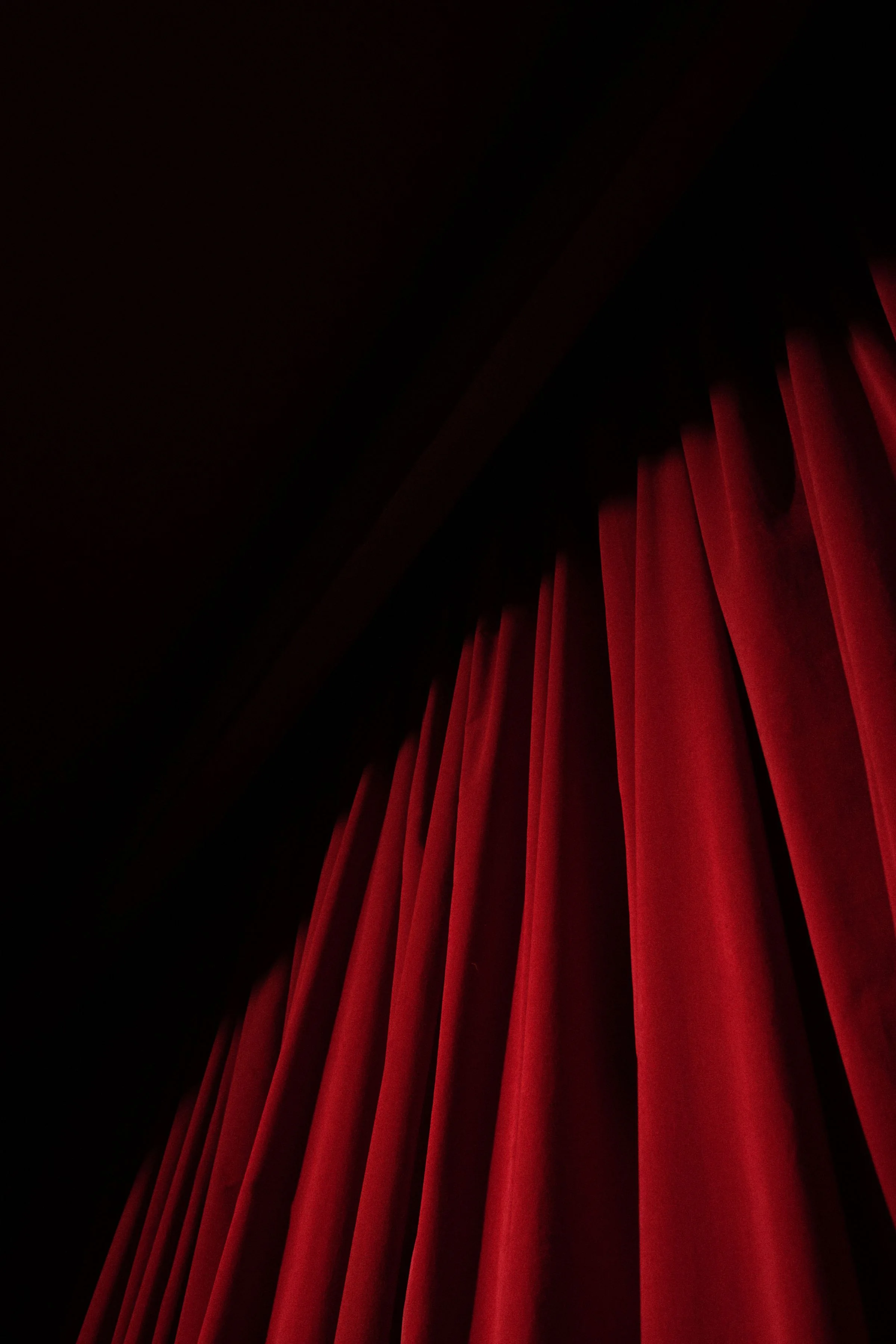 Red velvet theater curtain emerging from the darkness